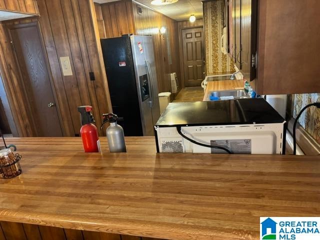 kitchen featuring appliances with stainless steel finishes, hardwood / wood-style flooring, wooden walls, and sink