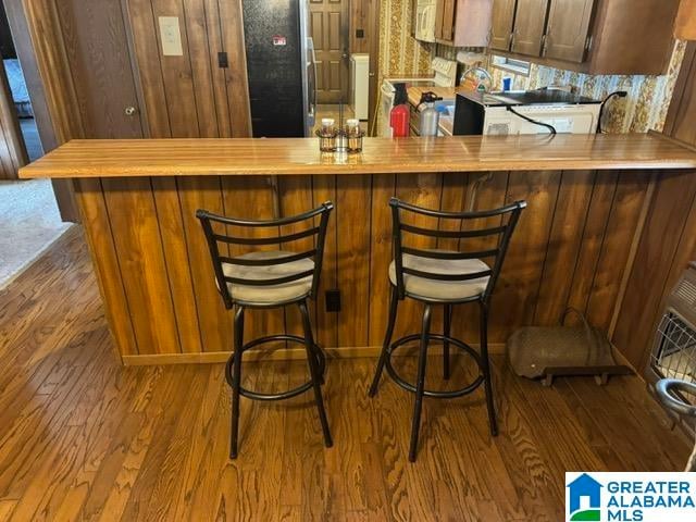 bar featuring black refrigerator, stove, and light wood-type flooring