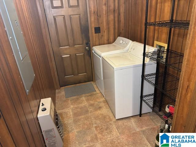 washroom with washing machine and dryer and wooden walls