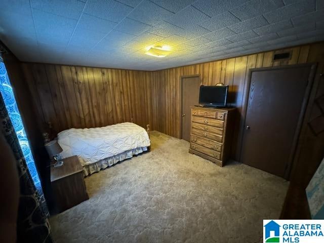 bedroom featuring carpet flooring and wooden walls