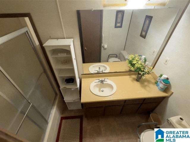 bathroom with toilet, a shower with door, and sink