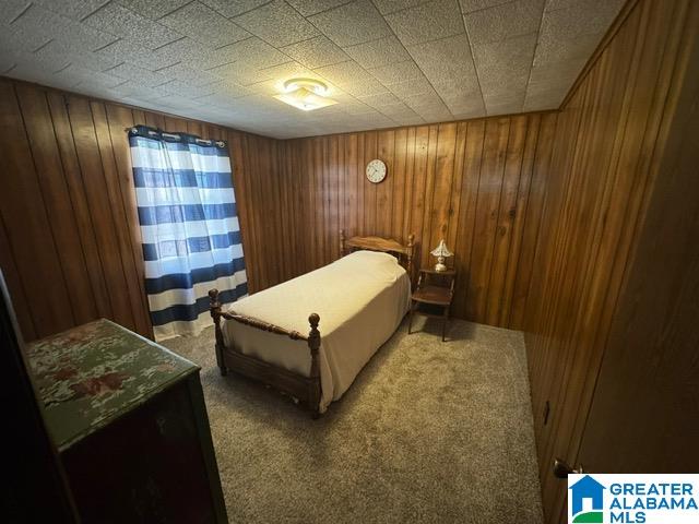 carpeted bedroom featuring wooden walls