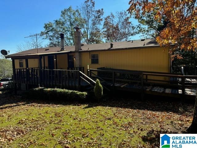 rear view of property featuring a lawn and a wooden deck