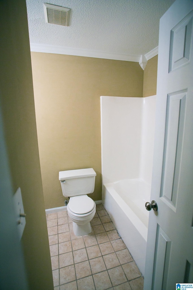 bathroom featuring tile patterned floors, ornamental molding, a textured ceiling, toilet, and a tub