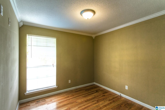 empty room with wood-type flooring, a textured ceiling, and ornamental molding