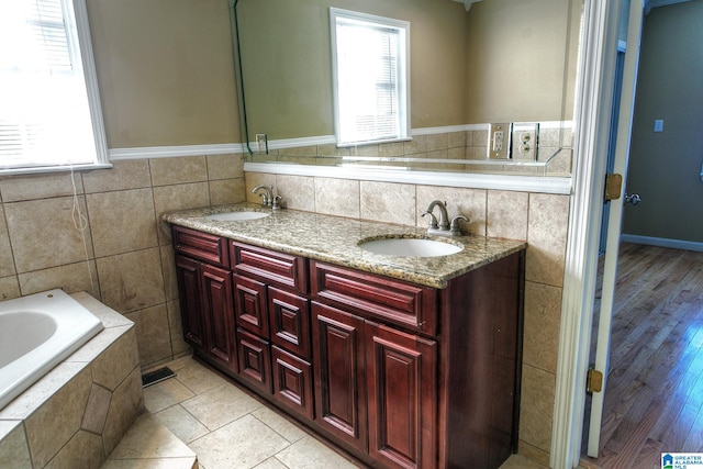 bathroom featuring hardwood / wood-style floors, vanity, a bath, and tile walls