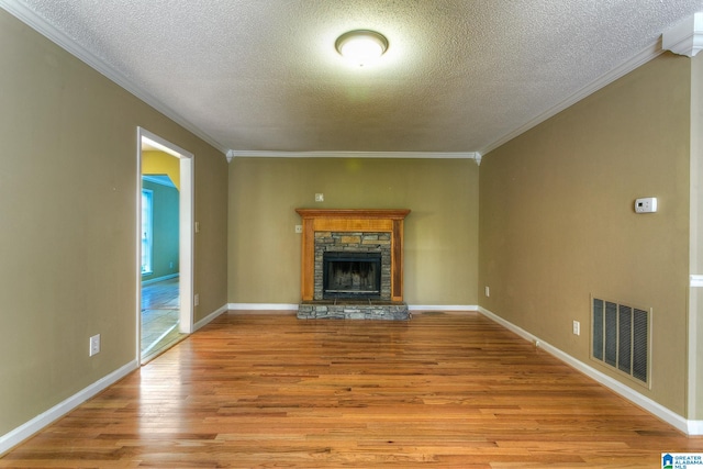 unfurnished living room with a textured ceiling, light wood-type flooring, a fireplace, and ornamental molding