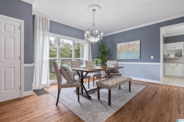 dining area with an inviting chandelier, light hardwood / wood-style flooring, and crown molding