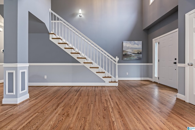 foyer with ornate columns, a towering ceiling, and wood-type flooring