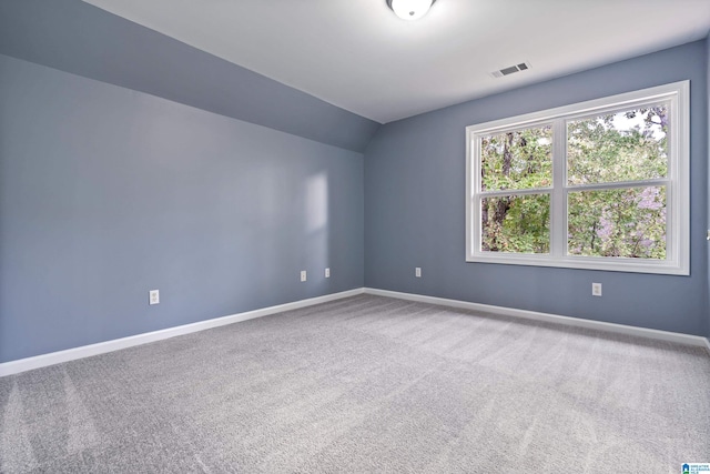 carpeted empty room with vaulted ceiling