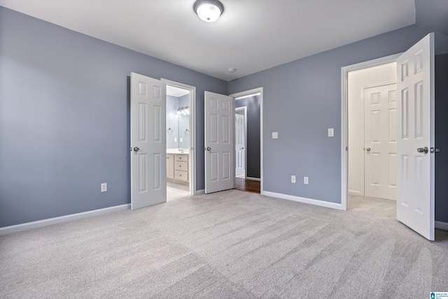 unfurnished bedroom featuring ensuite bathroom and light colored carpet