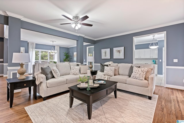 living room featuring ceiling fan with notable chandelier, light wood-type flooring, and ornamental molding