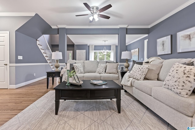 living room featuring hardwood / wood-style floors, ceiling fan with notable chandelier, and crown molding