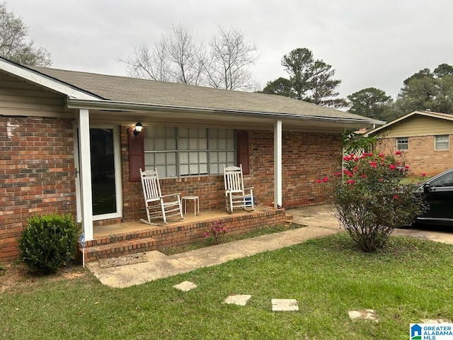 view of exterior entry featuring a porch and a yard