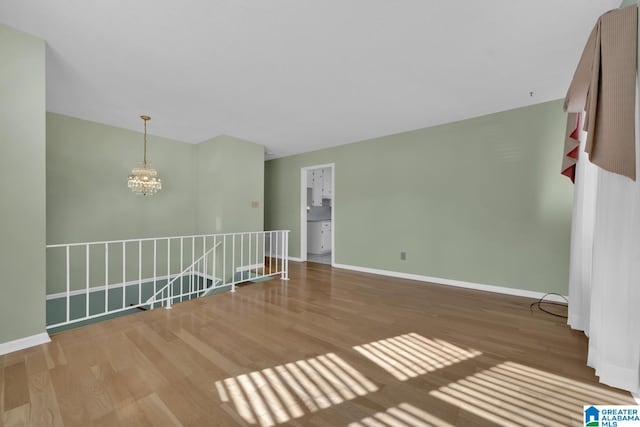 spare room with a notable chandelier and hardwood / wood-style flooring