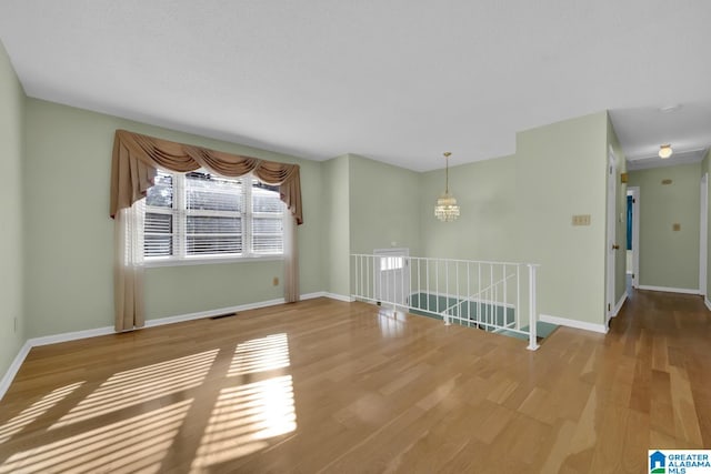 spare room featuring hardwood / wood-style flooring and an inviting chandelier