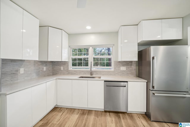 kitchen featuring light wood-type flooring, stainless steel appliances, white cabinetry, and sink