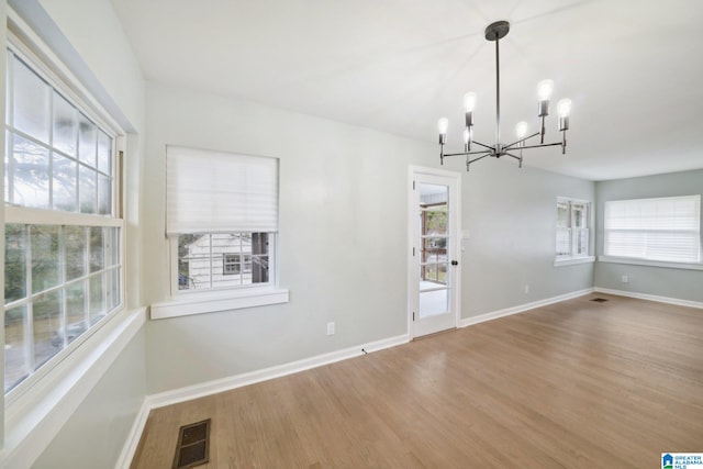 unfurnished dining area with hardwood / wood-style flooring and an inviting chandelier