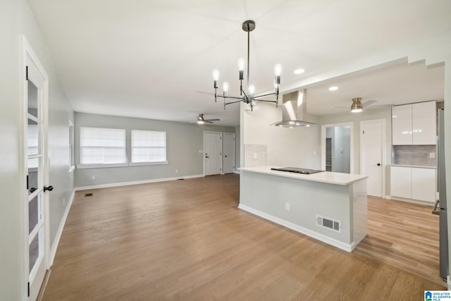 kitchen with pendant lighting, white cabinets, light wood-type flooring, tasteful backsplash, and kitchen peninsula