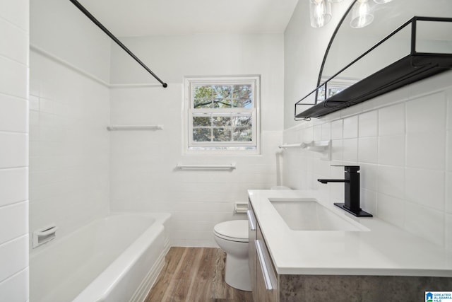 full bathroom featuring vanity, shower / bathing tub combination, wood-type flooring, tile walls, and toilet