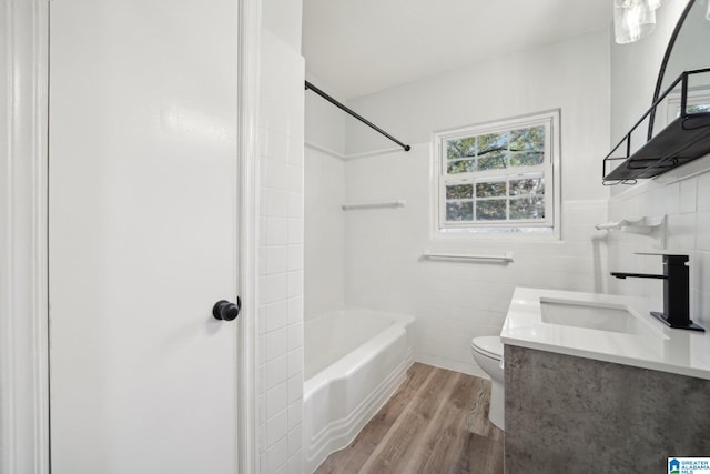 full bathroom with vanity, washtub / shower combination, hardwood / wood-style flooring, toilet, and tile walls