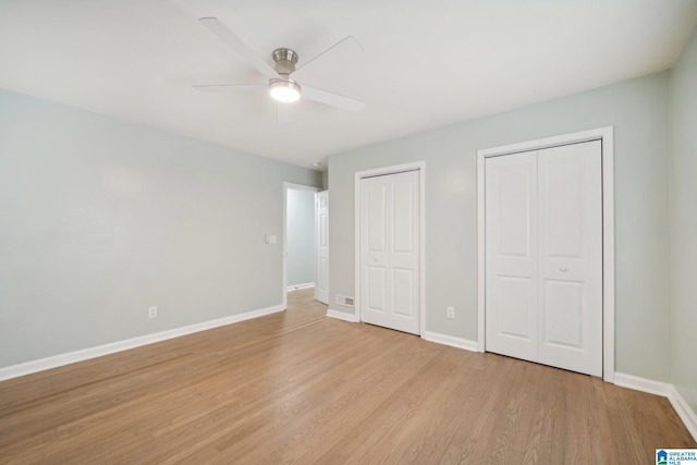 unfurnished bedroom featuring two closets, light hardwood / wood-style flooring, and ceiling fan