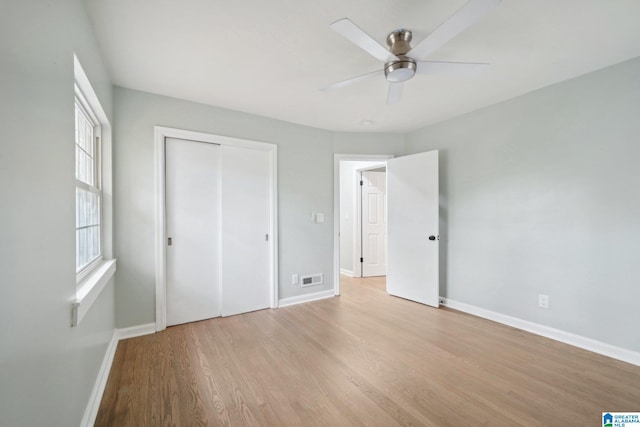 unfurnished bedroom with ceiling fan, a closet, and light wood-type flooring