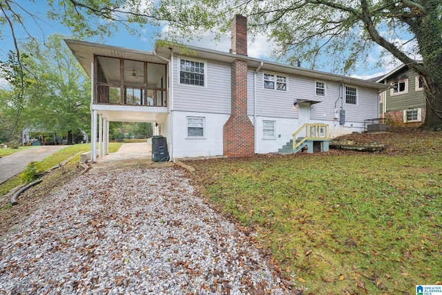 rear view of property with a lawn, a sunroom, ceiling fan, and a carport