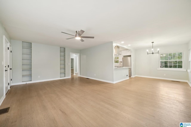 unfurnished living room featuring ceiling fan with notable chandelier, light wood-type flooring, and built in shelves