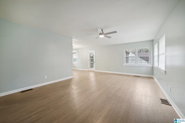 empty room with ceiling fan with notable chandelier and wood-type flooring