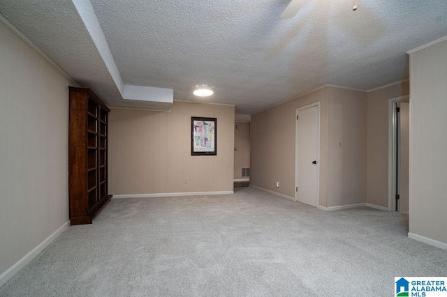 spare room with light colored carpet, ornamental molding, and a textured ceiling