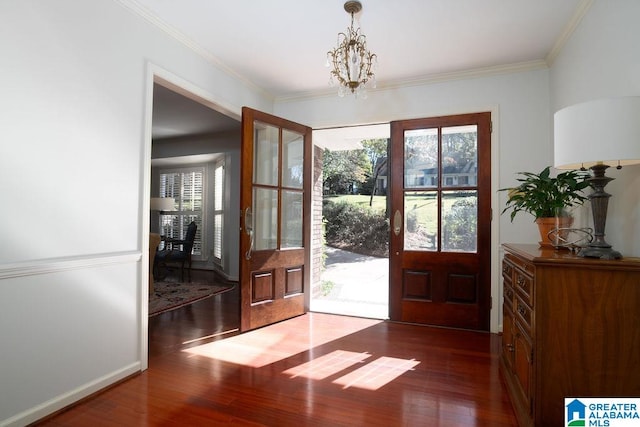 foyer with dark hardwood / wood-style floors, an inviting chandelier, and ornamental molding