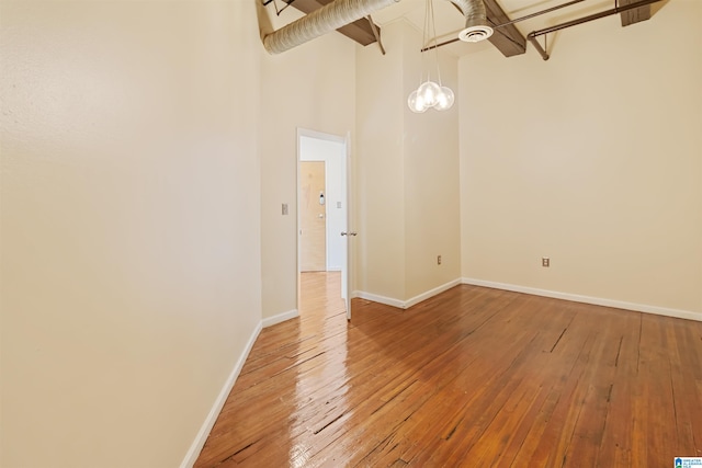 unfurnished room with hardwood / wood-style floors and a high ceiling