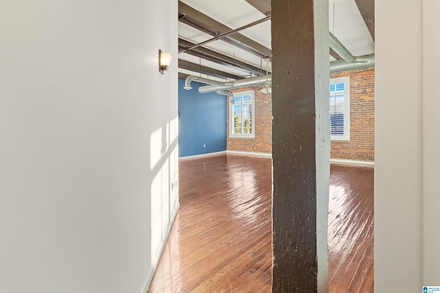 interior space with hardwood / wood-style flooring and brick wall