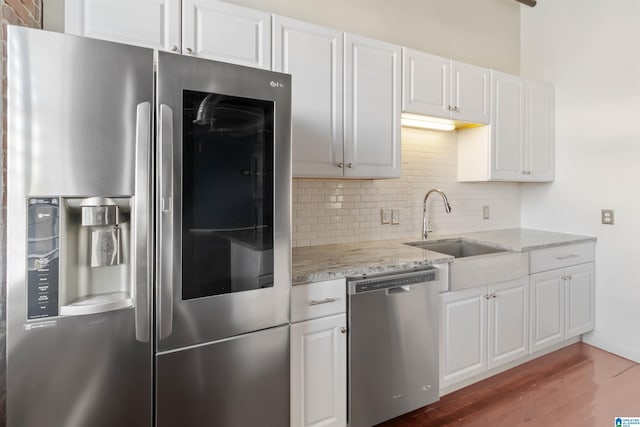 2301 1st Ave N Unit 203, Birmingham, AL 35203 - kitchen featuring appliances with stainless steel finishes, a sink, decorative backsplash, light stone counters, and white cabinets