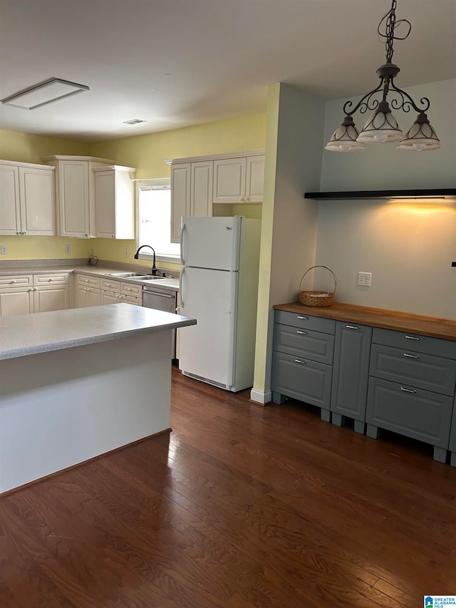 kitchen with white fridge, dark hardwood / wood-style flooring, white cabinetry, and hanging light fixtures