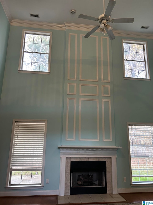 details featuring a tiled fireplace, crown molding, and ceiling fan