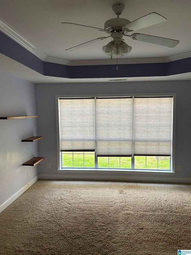 carpeted empty room featuring ceiling fan, ornamental molding, and a wealth of natural light