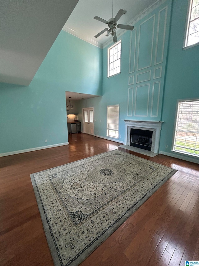 living room featuring ornamental molding, a towering ceiling, ceiling fan, and dark wood-type flooring