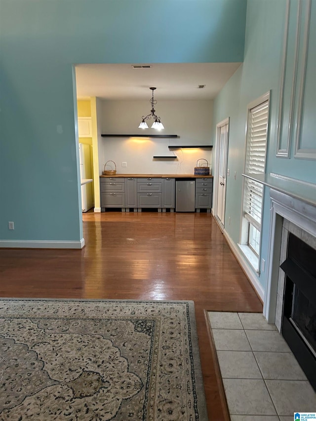 interior space with a tile fireplace, hanging light fixtures, stainless steel dishwasher, fridge, and light hardwood / wood-style floors