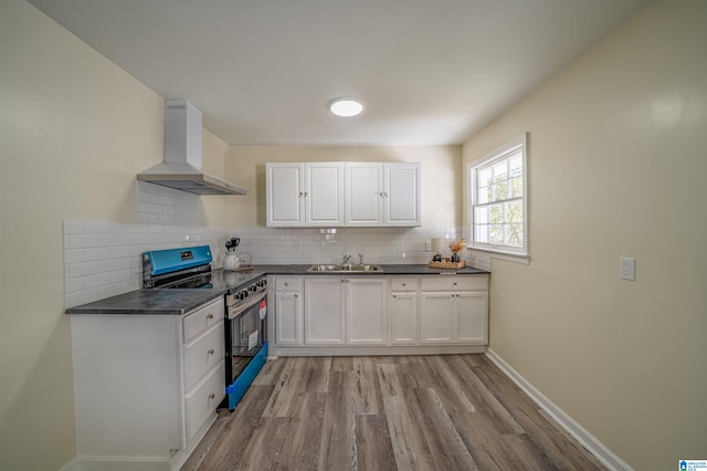 kitchen featuring sink, stainless steel range with electric stovetop, wall chimney range hood, decorative backsplash, and white cabinets