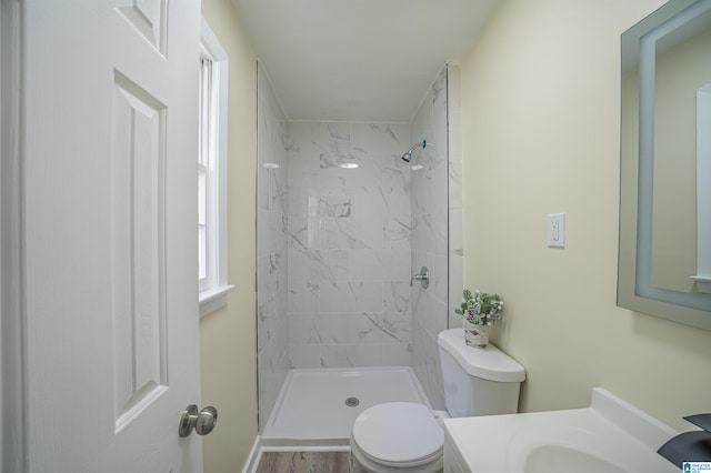 bathroom featuring vanity, tiled shower, and toilet