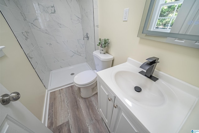 bathroom featuring vanity, wood-type flooring, toilet, and tiled shower