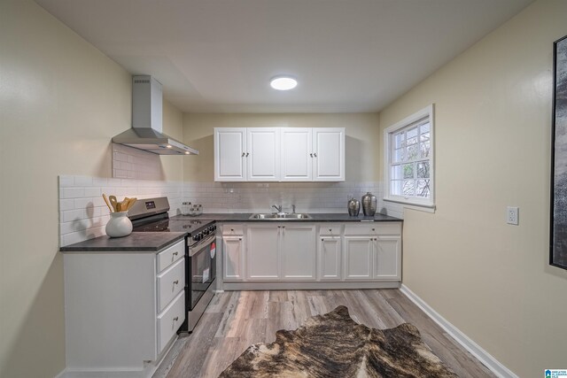 kitchen featuring stainless steel electric range, sink, white cabinets, and wall chimney exhaust hood