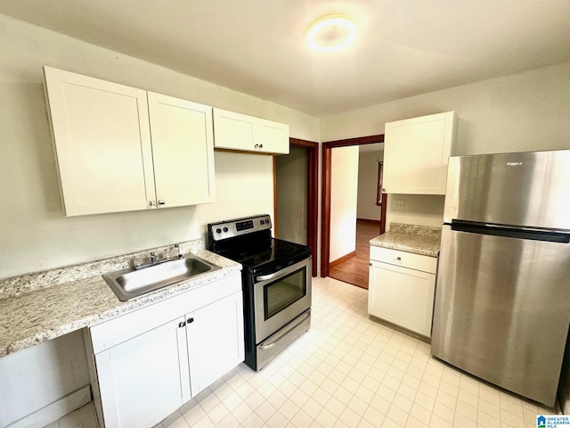 kitchen featuring light stone countertops, white cabinetry, sink, and appliances with stainless steel finishes