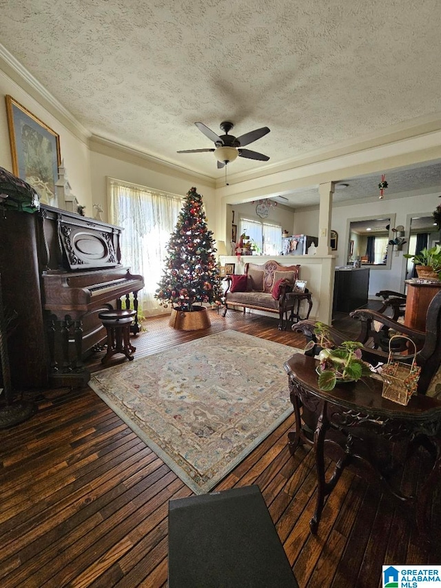 living room with ceiling fan, crown molding, dark wood-type flooring, and a textured ceiling