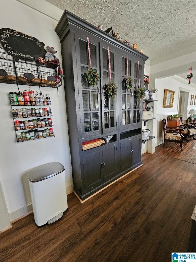 bar featuring a textured ceiling and dark wood-type flooring