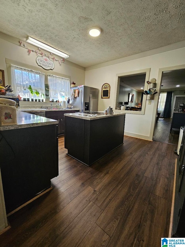 kitchen featuring stainless steel fridge, a center island, a textured ceiling, and dark hardwood / wood-style flooring