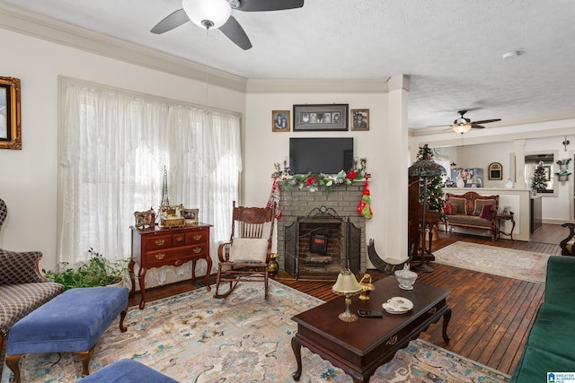 923 Cogswell Ave, Pell City, AL 35125 - living room featuring ceiling fan, wood-type flooring, ornamental molding, a fireplace, and a textured ceiling