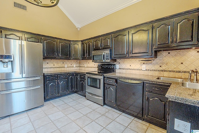 kitchen featuring backsplash, crown molding, vaulted ceiling, light tile patterned floors, and stainless steel appliances